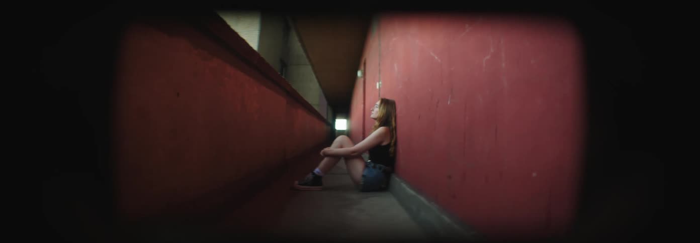 Young blonde woman sitting in a hallway of a building