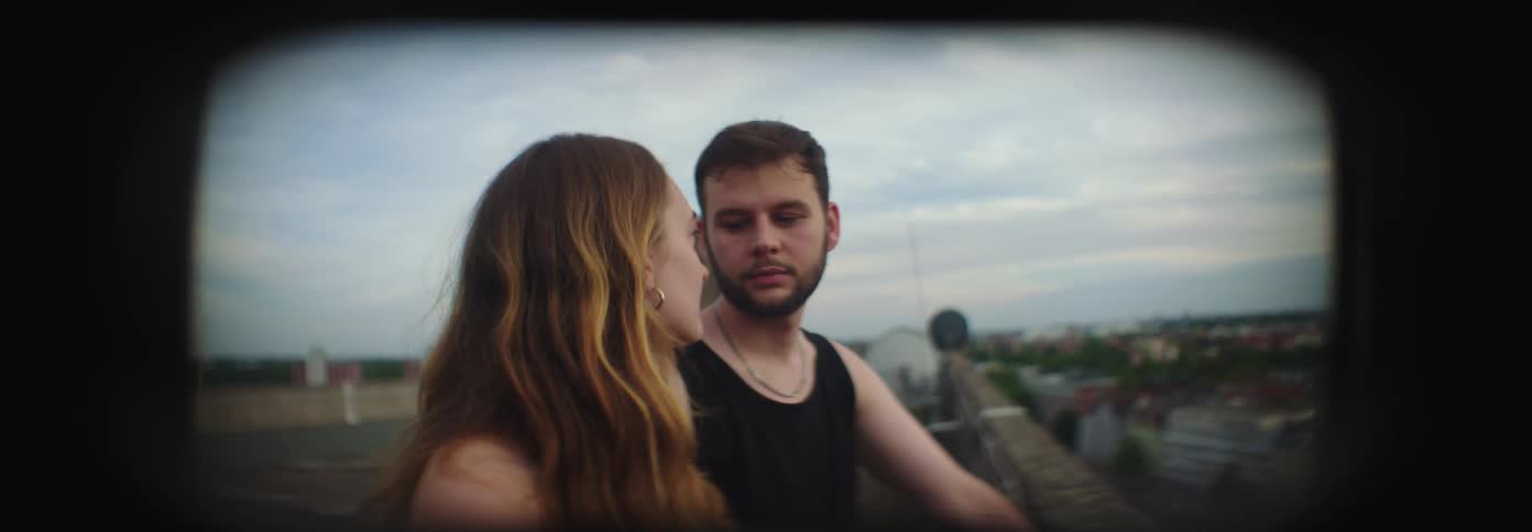 A man and woman are looking at each other while standing on an outdoor walkway in a residential neighborhood in the evening