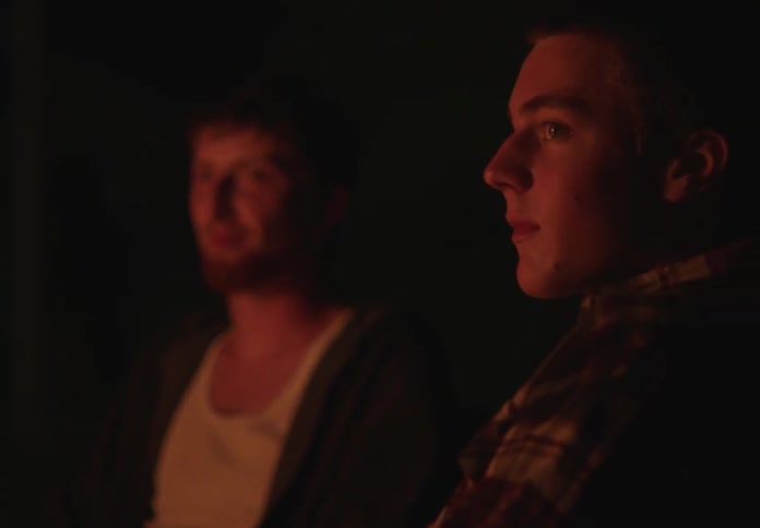 Portrait of two men sitting outdoors at night with a slight smile