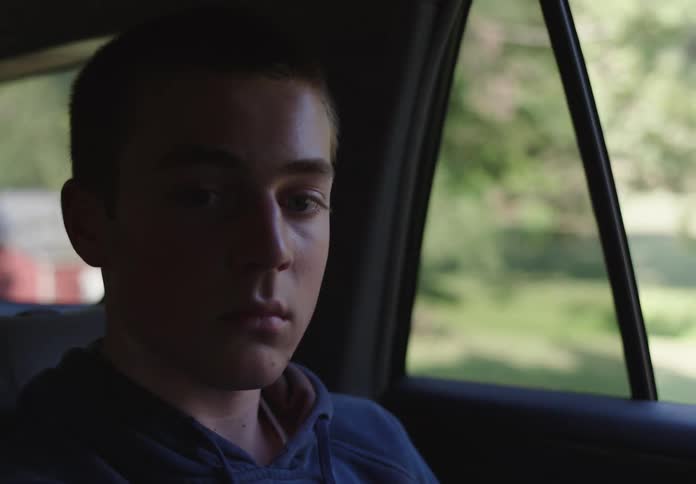A sad boy watching the landscape through the car window
