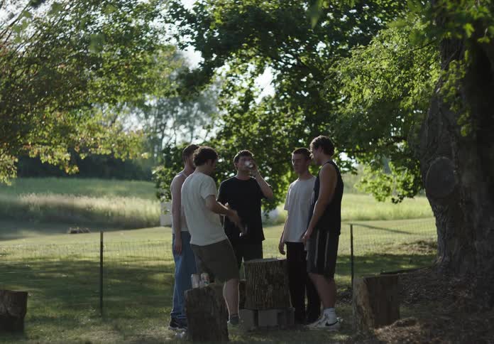 Friends in an outdoor setting in a circle playing with a hammer