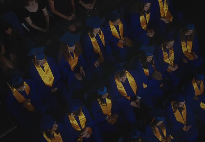 Graduating seniors talk among themselves next to attending audience