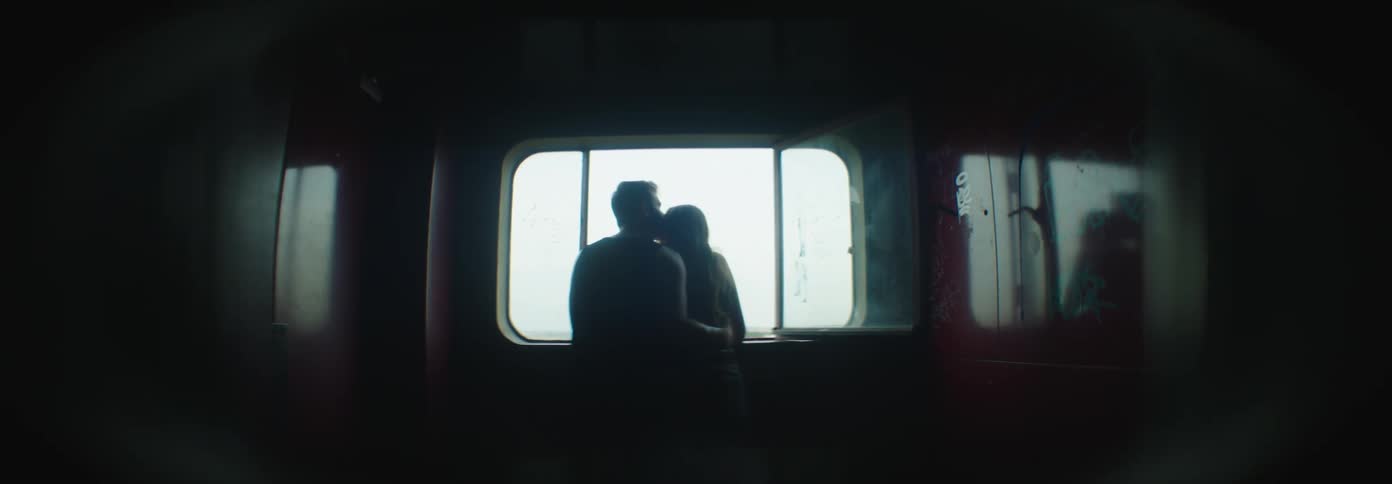 A man and woman kiss by the window