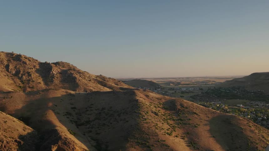 Landscape of a sandy and hilly area is shown at sunset