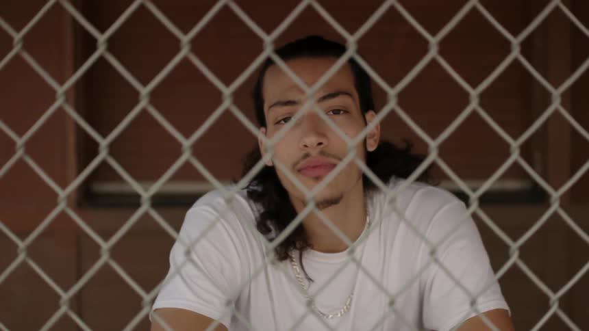 A man looks up from behind a fence