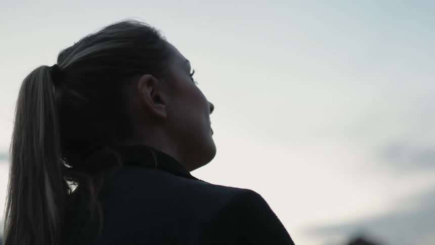 A woman looks up at a cloudy sky