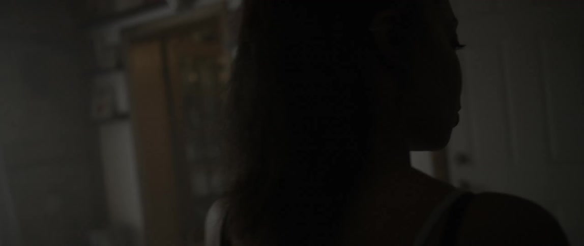 A woman enters a kitchen and puts a bowl down