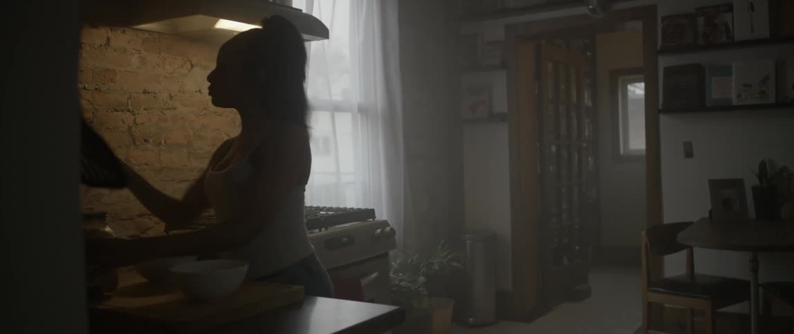 A woman walks into a kitchen with a bowl and jar