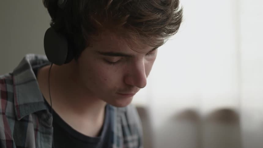 A man is wearing headphones and looking down