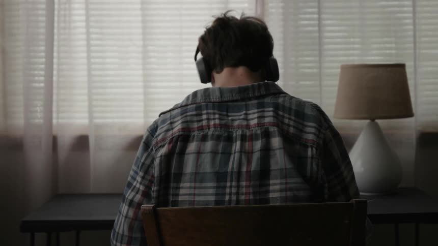 A man is sitting at a desk wearing headphones