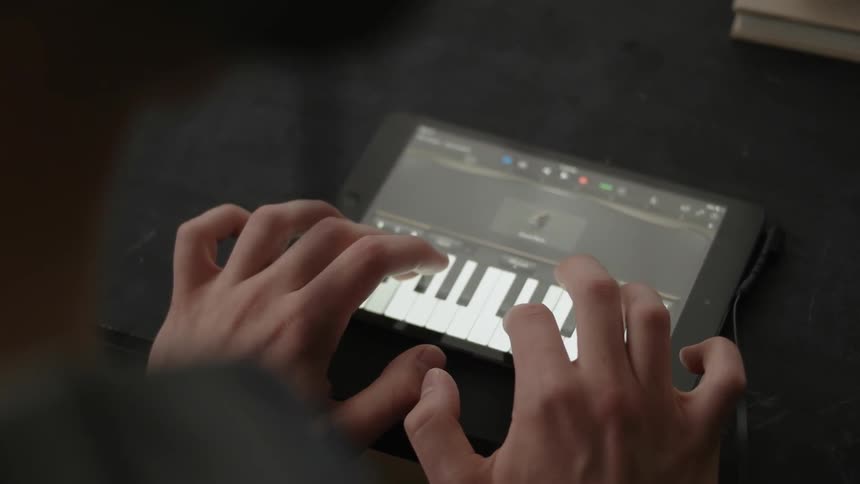 A man is playing keyboard on a tablet