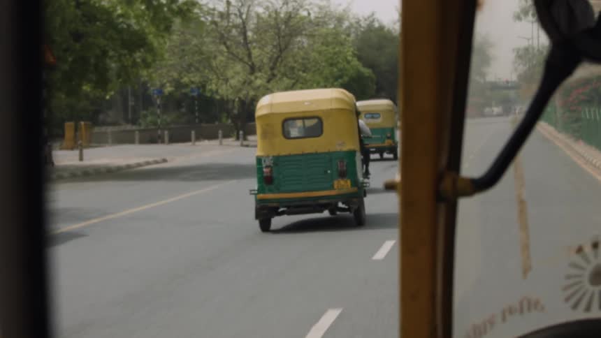Old cars traveling down a road