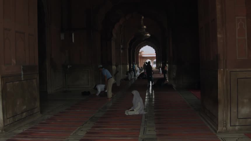 A long dark hall has many people praying
