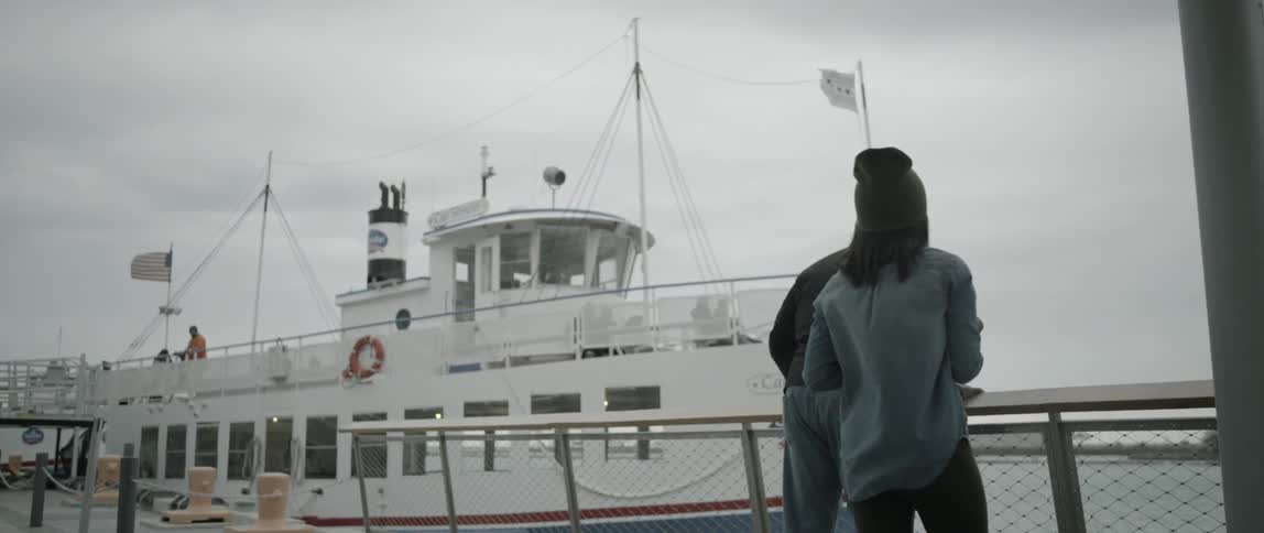 A woman is taking photos of a ship docking