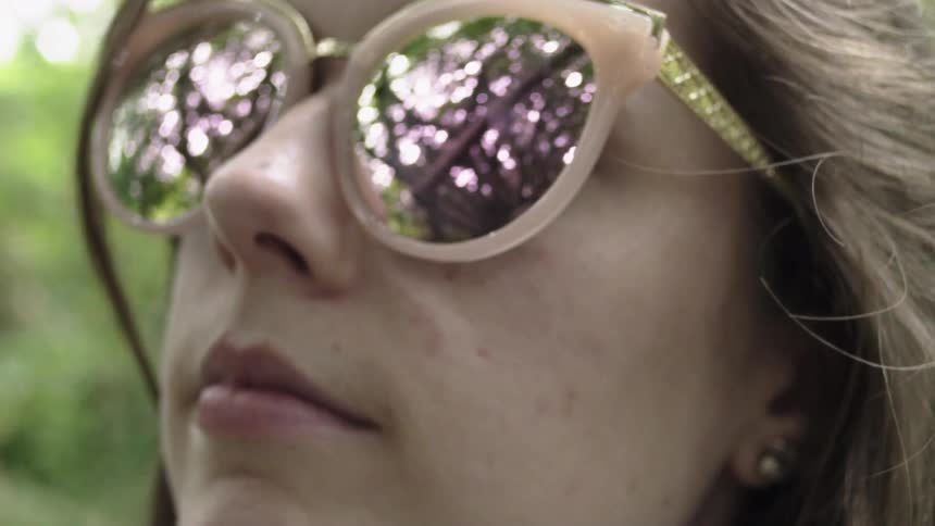 A woman looks up wearing large sunglasses