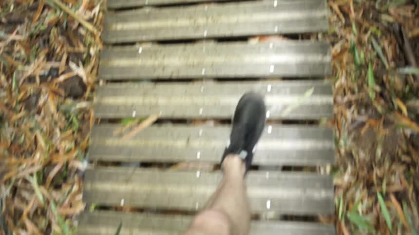 A man's feet walk on a board walkway