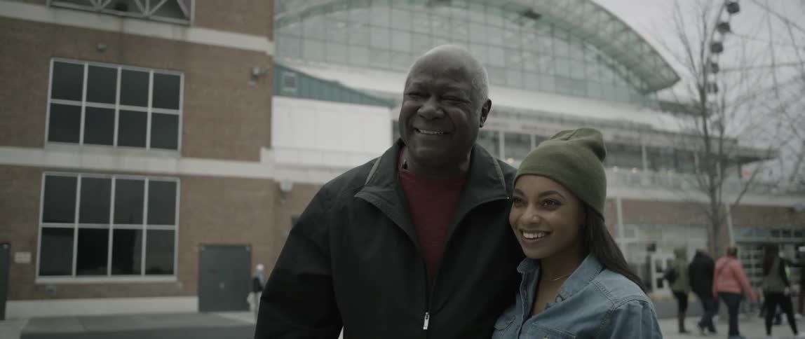 A man and woman stand together smiling