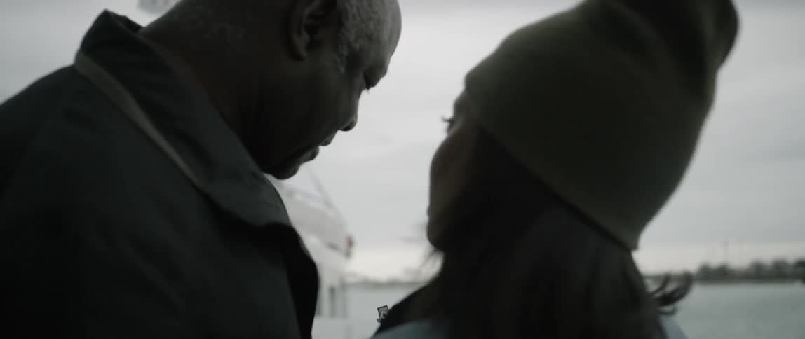 A man and woman stand near a boat looking at a camera