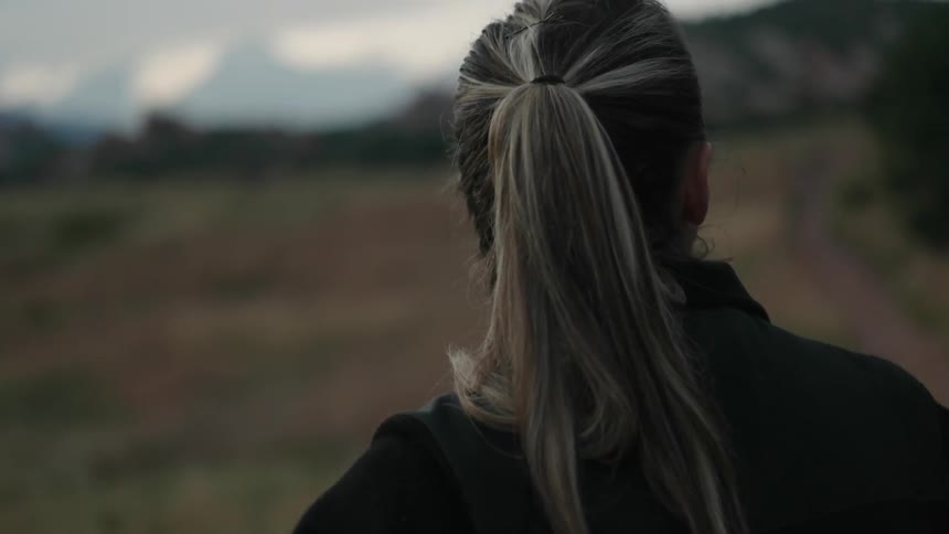 A woman looks over a hilly field ahead