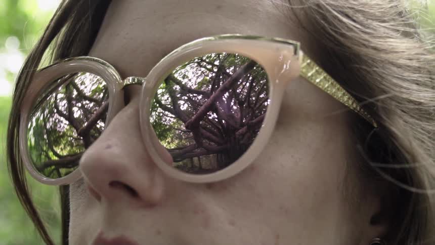 A woman is wearing large reflective sunglasses