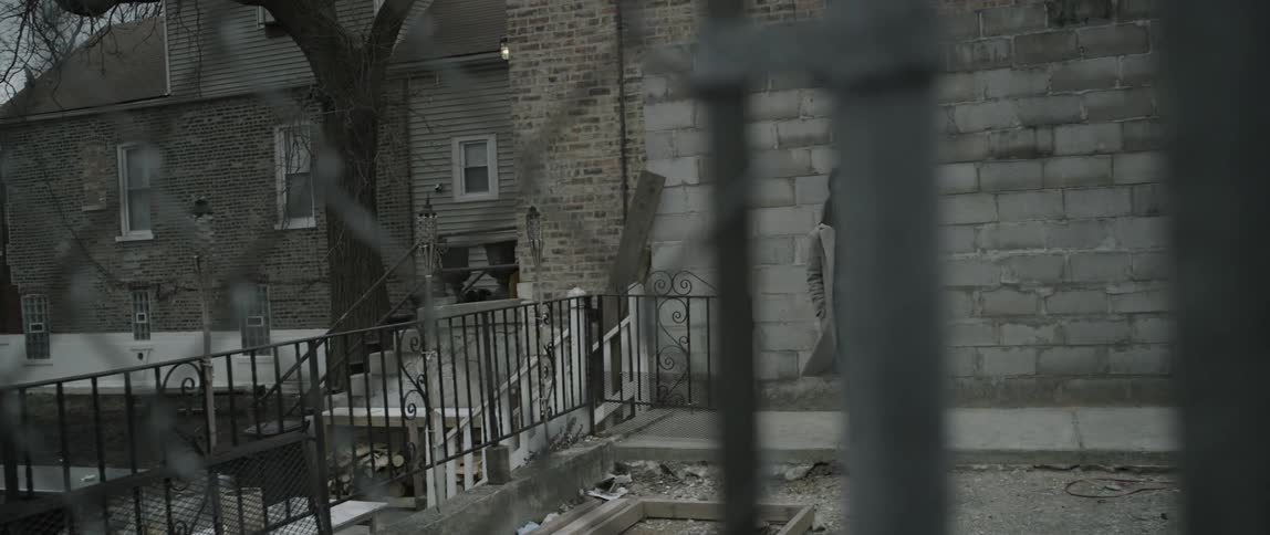 Woman exits a building and leaves through a chainlink fence