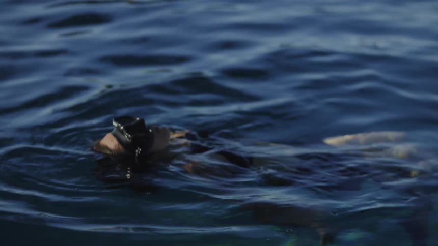 A person with diving goggles floating in the water