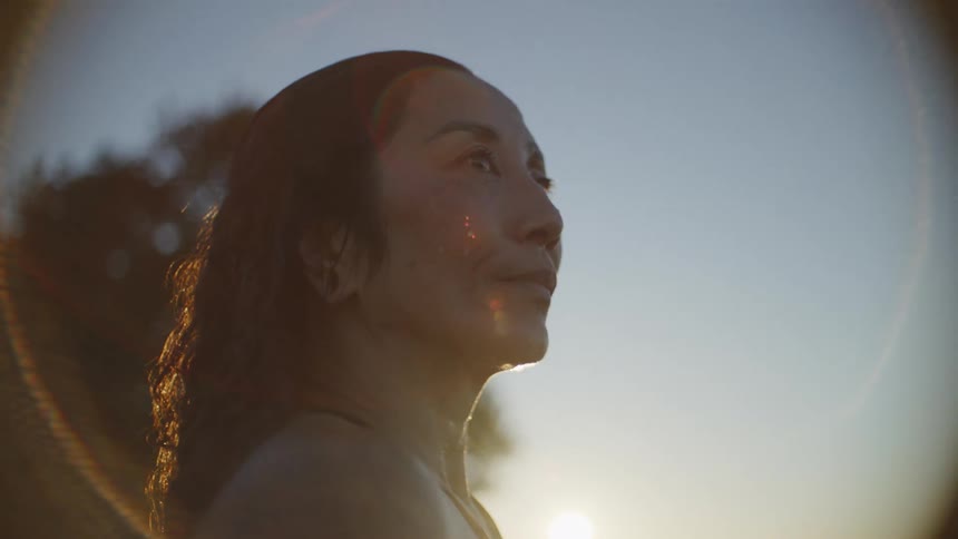 Profile of a woman in front of the sun