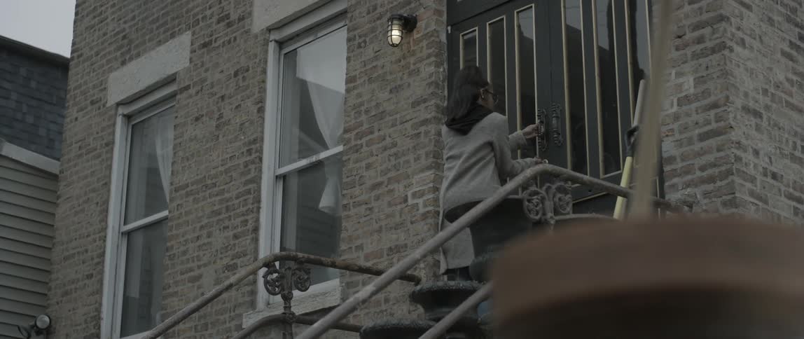 A woman leaves her home and locks the door before walking down the steps
