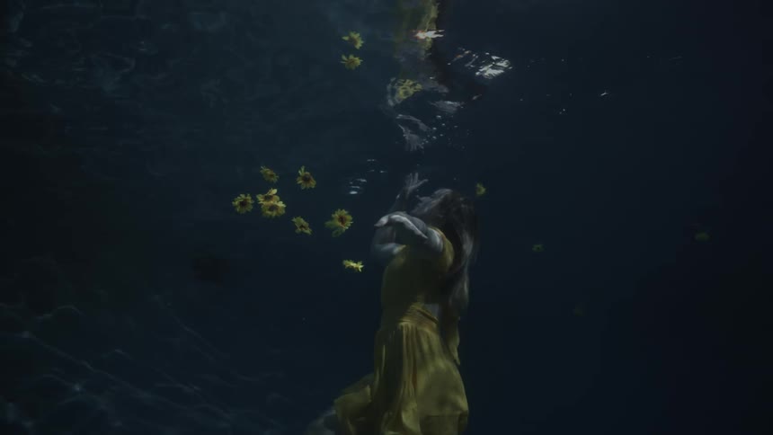 Woman in a yellow dress rising to the surface of the water as sunflowers sink around her