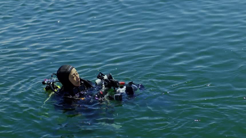 Woman in diving gear in the ocean adjusts camera