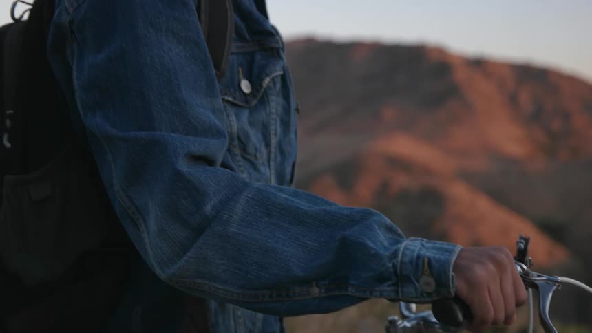 A man wearing a backpack looks out at a valley