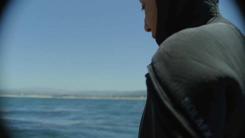 A scuba diver puts on gloves and prepares to enter the ocean