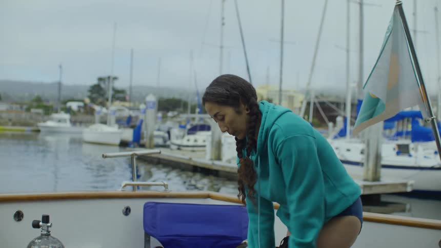 Woman wears a wetsuit on a boat