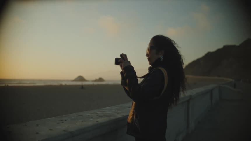 Woman takes pictures of the ocean at sunset