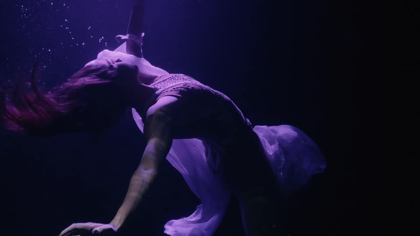 Woman dancer floats underwater towards the surface