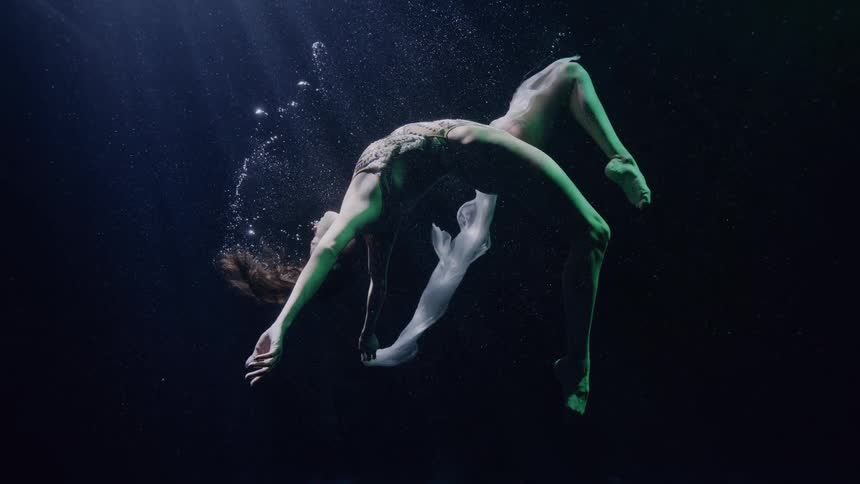 Artistic swimmer performs a dance underwater