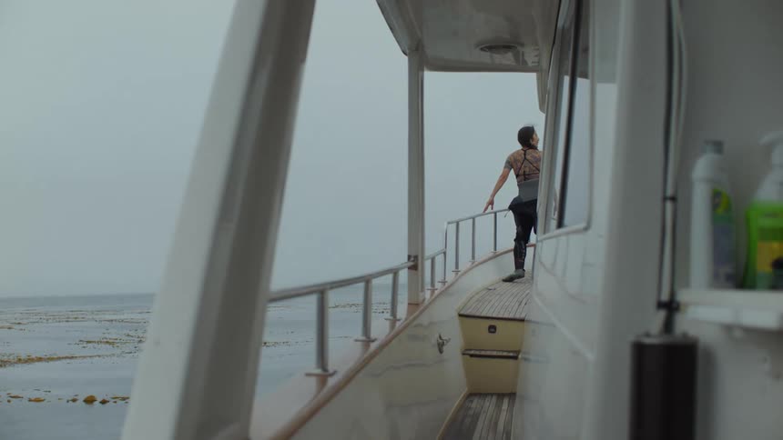 A woman peers over the railing while on a large boat on the ocean