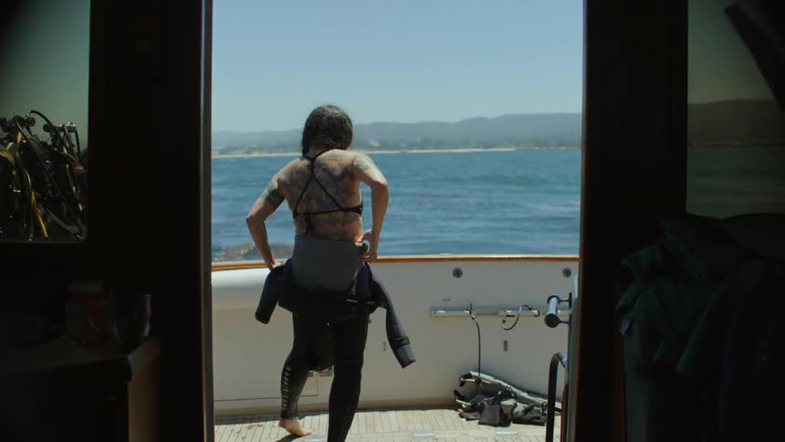 Woman puts on a wetsuit to dive into the ocean