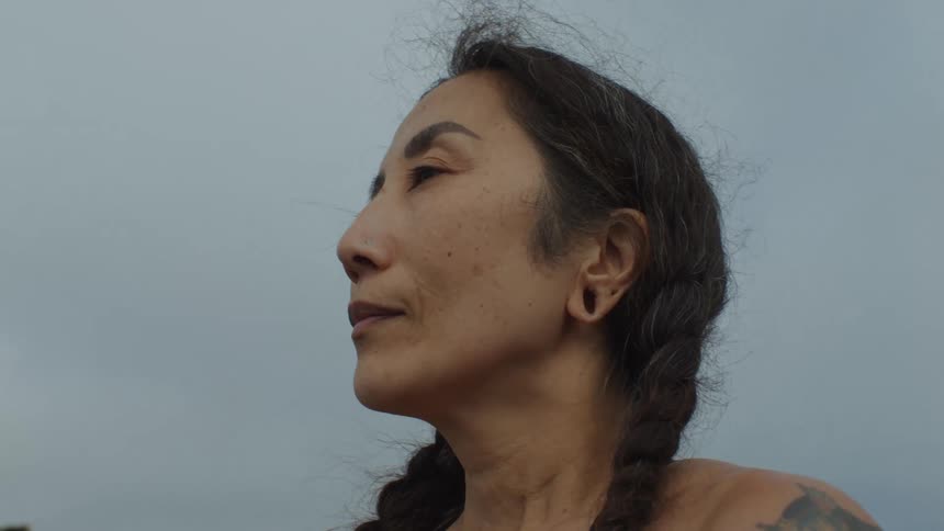 Face of a tattooed woman taking deep breaths at the beach