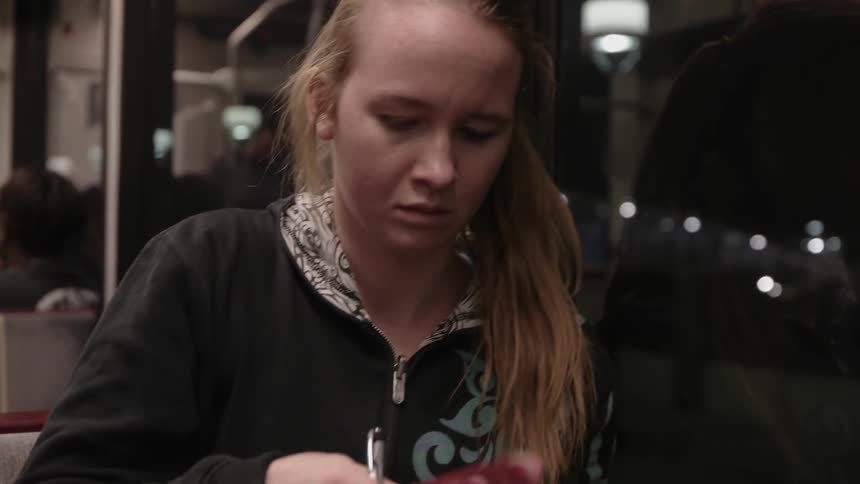 A girl pulls a binder out of her backpack while riding public transit