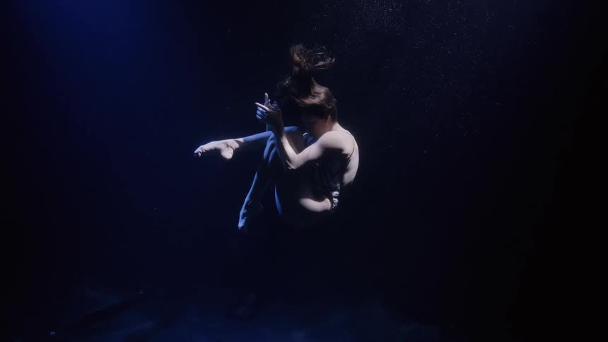Artistic swimmer performs at the bottom of a pool