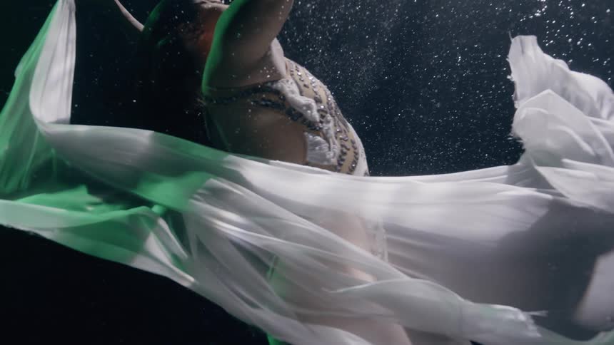 Artistic swimmer in a pool is performing and dancing