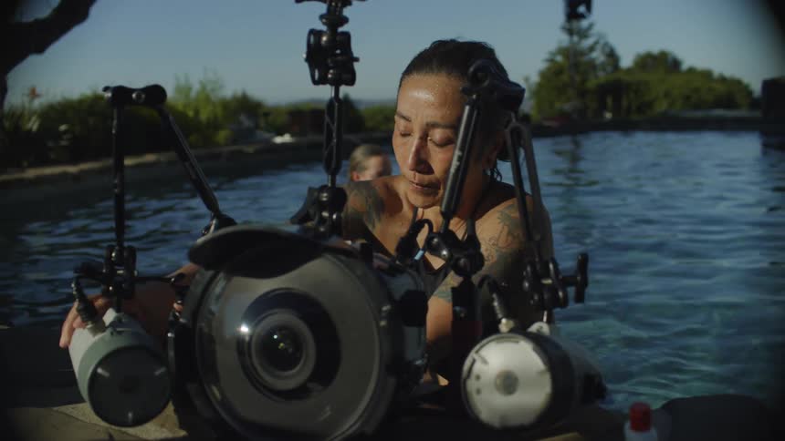 Woman checks an underwater camera by the pool