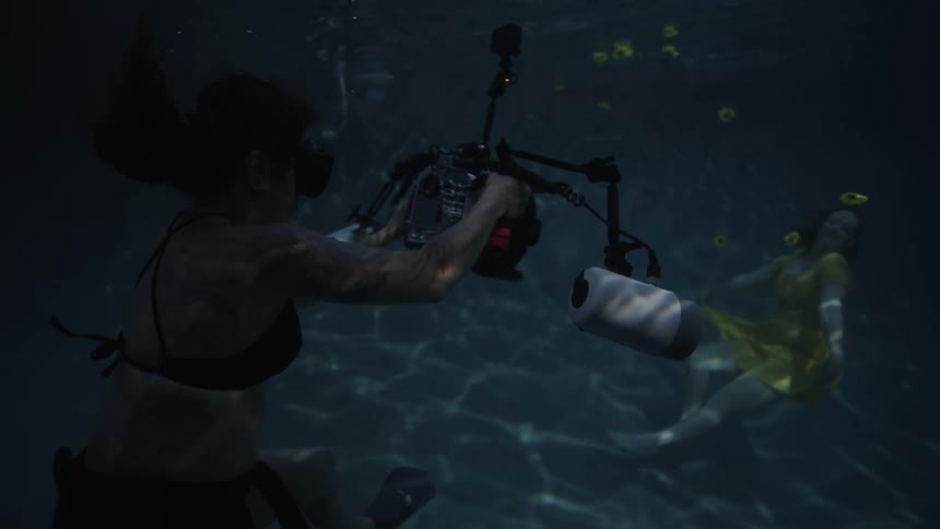 A photographer taking photos at the bottom of a pool