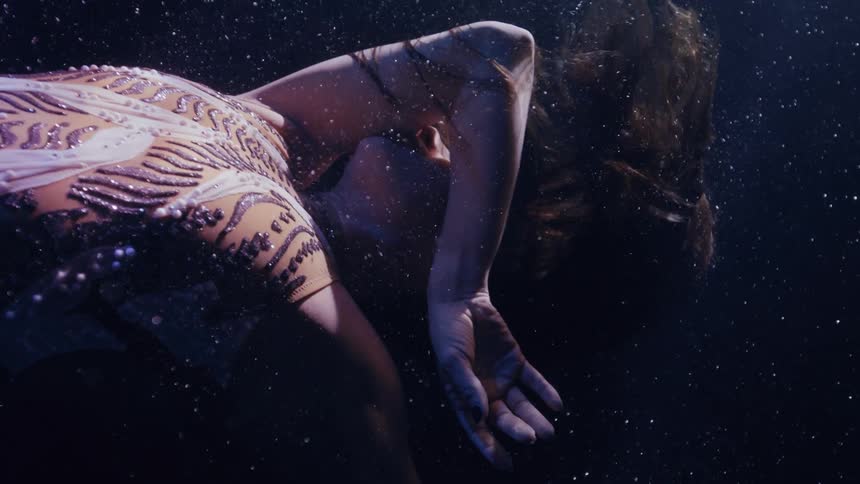 A woman is dancing and performing underwater