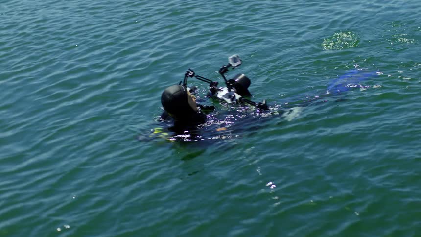 Scuba diver swims back to the boat with a camera