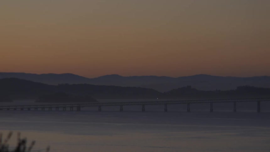 A bridge over the sea with mountains in the background at dusk in San Francisco