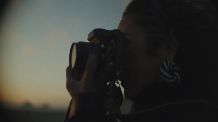 Woman takes pictures of a beach at sunset