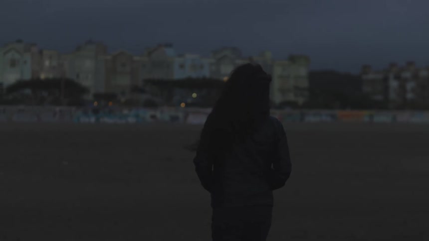 Woman walking away on the beach at night