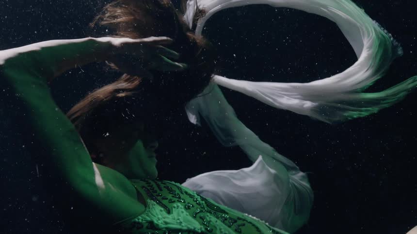 Woman dances underwater in a pool